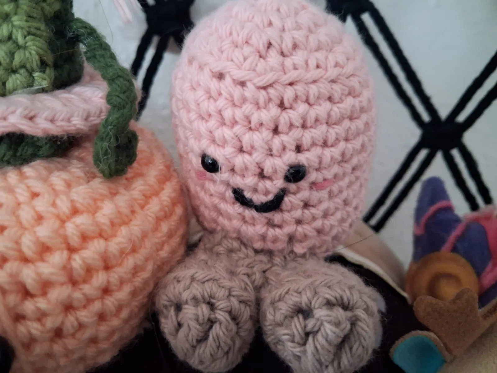 A pink crochet stuffed friend with a stitched smile, rosy cheeks and tan feet